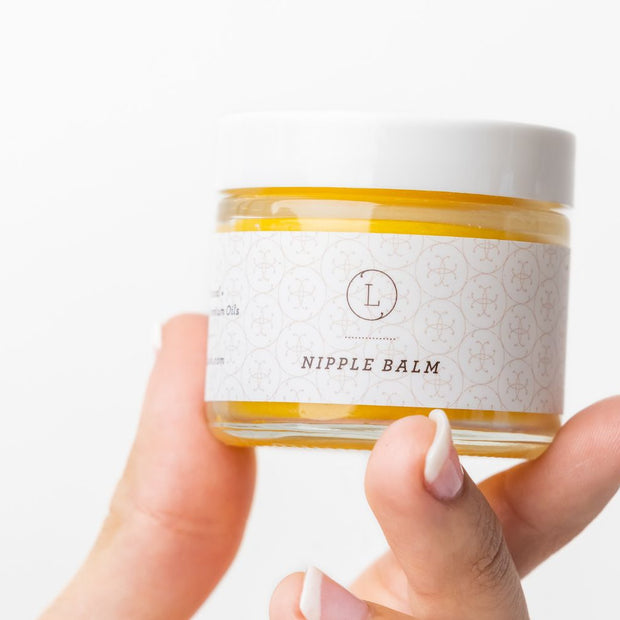 Natural organic nipple balm in a smal jar - held in a hand